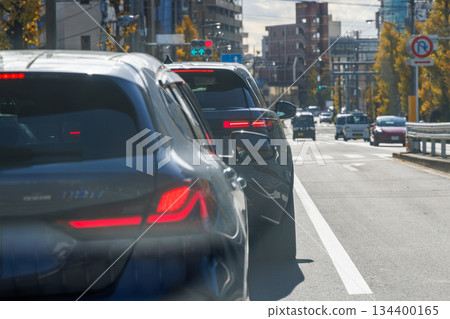 Red taillights of a car waiting at a traffic light on the road 134400165