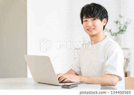 Young Asian man using a laptop in the living room at home (individual investor, investor, investment, asset management) 134400565