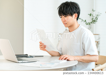 Young Asian man using laptop in the living room at home (documents, document creation, editing) Young Asian man using laptop in the living room at home (documents, document creation, editing) 134400613
