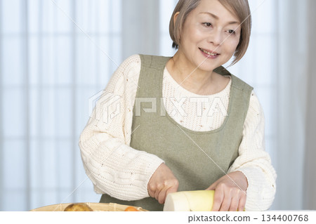 Senior woman peeling vegetables in the kitchen Senior woman peeling vegetables in the kitchen 134400768