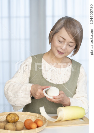 Senior woman peeling vegetables in the kitchen 134400780