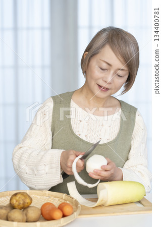 Senior woman peeling vegetables in the kitchen Senior woman peeling vegetables in the kitchen 134400781