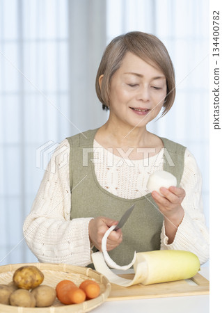 Senior woman peeling vegetables in the kitchen Senior woman peeling vegetables in the kitchen 134400782