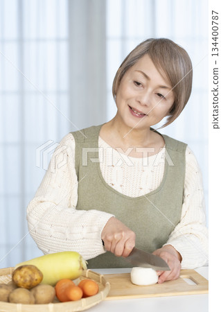Senior woman peeling vegetables in the kitchen Senior woman peeling vegetables in the kitchen 134400787