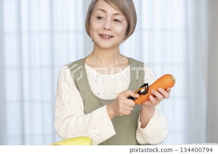 Senior woman peeling vegetables in the kitchen Senior woman peeling vegetables in the kitchen 134400794