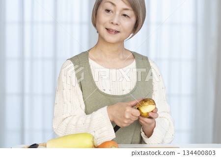 Senior woman peeling vegetables in the kitchen Senior woman peeling vegetables in the kitchen 134400803