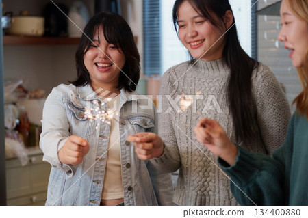 Three friends celebrating with sparklers in a cozy kitchen Three friends celebrating with sparklers in a cozy kitchen 134400880