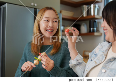 Healthy Cooking. Friends enjoying food preparation and sharing smiles in the kitchen. 134400881