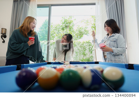 Friends enjoying a game of pool at a lively party Friends enjoying a game of pool at a lively party 134400894