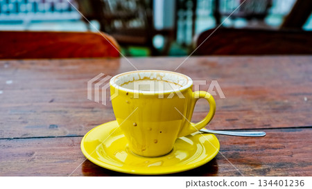 Close-up photo of a yellow cup on a brown table 134401236