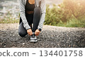 Closeup, exercise and woman outdoor, tie shoes and training with fitness, workout goal and target. Female person, athlete and runner with marathon, practice and sports with wellness, start and health 134401758