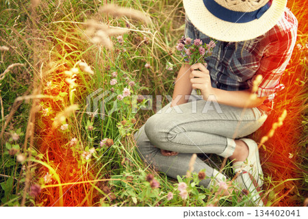 Lens flare, field and woman picking flower in countryside for freedom, wellness and fresh air outdoors. Wildflowers, spring and hipster female person in meadow for relax or sustainability in nature Lens flare, field and woman picking flower in countryside for freedom, wellness and fresh air outdoors. Wildflowers, spring and hipster female person in meadow for relax or sustainability in nature 134402041