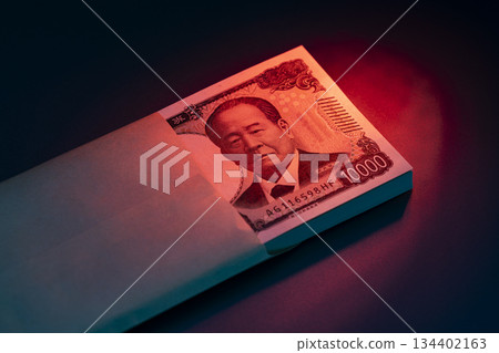 Financial concept with a stack of 10,000 yen bills and an envelope illuminated by red light 134402163