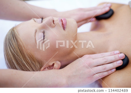 Hands of masseuse, woman with hot stone massage in spa and healing holistic treatment with zen at luxury wellness resort. Rocks on shoulders, peace with therapy and alternative medicine for self care 134402489