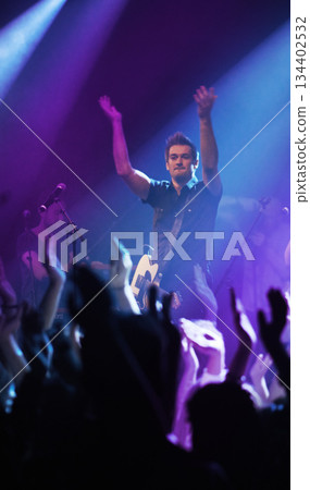 People hands, music and singer at concert in night performance, rock band or gen z in neon lights or cheers. Musician man on stage at disco event and fans clapping, crowd or audience dancing on floor 134402532