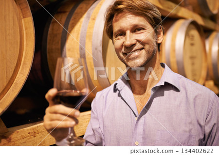 Portrait, wine and taste with a man in the cellar of a distillery on a farm for production or fermentation of alcohol. Glass, winery and barrel with a male farmer tasting a drink for quality control Portrait, wine and taste with a man in the cellar of a distillery on a farm for production or fermentation of alcohol. Glass, winery and barrel with a male farmer tasting a drink for quality control 134402622