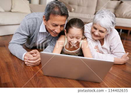 Laptop, floor or grandparents with happy child for movie streaming online subscription in retirement at home. Girl, relaxing together or grandmother watching videos on internet with a senior old man 134402635