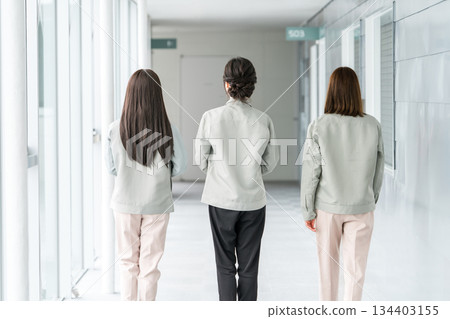 Female staff from the manufacturing, construction, transportation and construction industries wearing work clothes walking down the corridor of an office building Female staff from the manufacturing, construction, transportation and construction industries wearing work clothes walking down the corridor of an office building 134403155