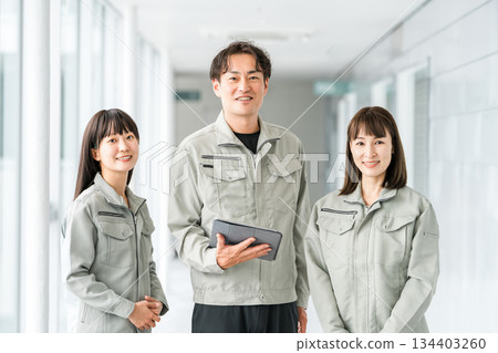 Male and female staff in the manufacturing, building, transportation, and construction industries wearing work clothes. 134403260