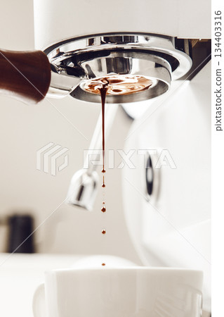 Close-up of Coffee Extraction From Bottomless Portafilter Against Bright Background, Highlighting Brewing Process in Detail Close-up of Coffee Extraction From Bottomless Portafilter Against Bright Background, Highlighting Brewing Process in Detail 134403316
