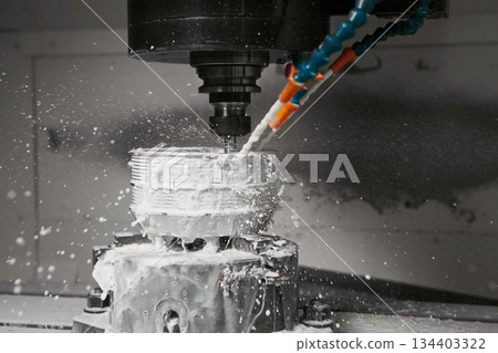 CNC milling machine cutting aluminium automotive part with a coolant liquid. Hi-Technology manufacturing process. CNC milling machine cutting aluminium automotive part with a coolant liquid. Hi-Technology manufacturing process. 134403322