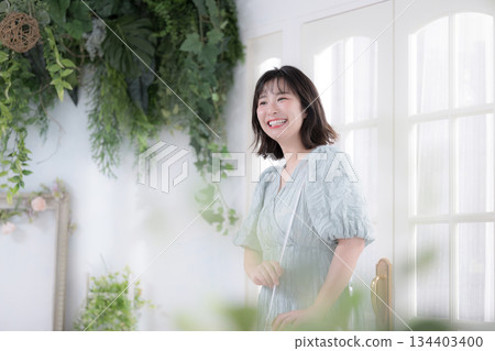 一位年輕女性面帶微笑地在可愛的商店裡挑選少女風時尚服飾。 134403400