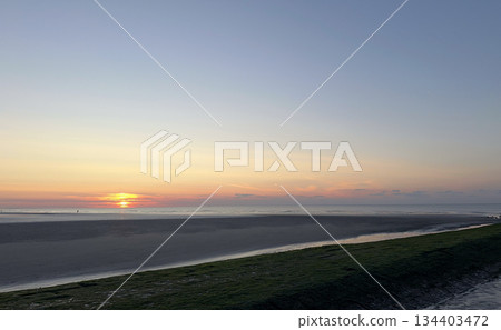 A Serene Beach Sunset Over the Calm Waters, creating a tranquil and picturesque atmosphere A Serene Beach Sunset Over the Calm Waters, creating a tranquil and picturesque atmosphere 134403472