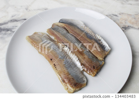 Pieces of herring fillet on a plate View from above. Preparation of fish dishes. horizontal photo. 134403483