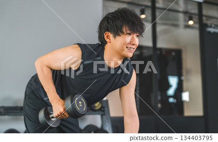 Young Asian man doing dumbbell training at fitness gym Young Asian man doing dumbbell training at fitness gym 134403795
