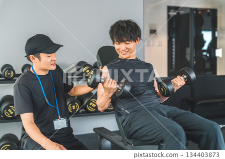 健身房裡，男教練和男教練正在進行啞鈴訓練。 134403873