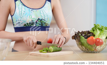 Meal Preparation. Woman slicing cucumber for healthy meal, promoting cooking skills. Meal Preparation. Woman slicing cucumber for healthy meal, promoting cooking skills. 134404051