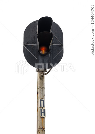 A weathered railway signal towers above a rusted pole, with a glowing red light 134404703