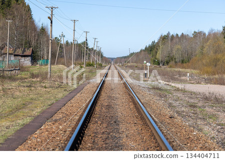 A lone straight railway line runs through a quiet rural landscape 134404711