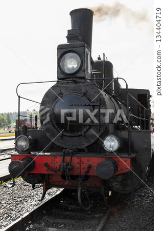 A historic steam locomotive faces the camera on a railway track 134404719