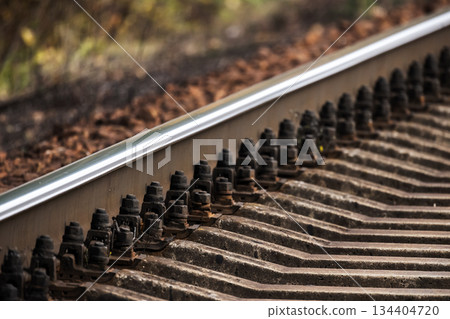 A close-up view of railroad tracks highlighting bolts, rails, and concrete sleepers A close-up view of railroad tracks highlighting bolts, rails, and concrete sleepers 134404720