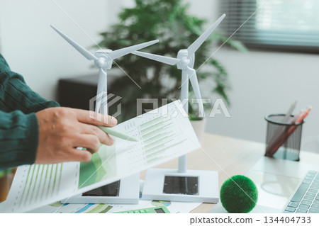 Eco-friendly business concept with hand analyzing financial charts and green earth globe symbolizing sustainable investment, environmental data analysis and green economy growth. green business. 134404733