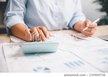 Close-up of office worker calculating financial data using calculator reviewing receipts business reports desk illustrating accounting tasks budgeting expense tracking professional financial workflow Close-up of office worker calculating financial data using calculator reviewing receipts business reports desk illustrating accounting tasks budgeting expense tracking professional financial workflow 134404736