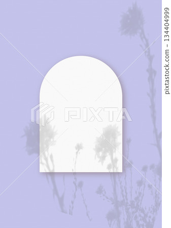 Natural light casts shadows from wildflowers on an arched sheet of white paper lying on a vertical purple background. Mockup 134404999