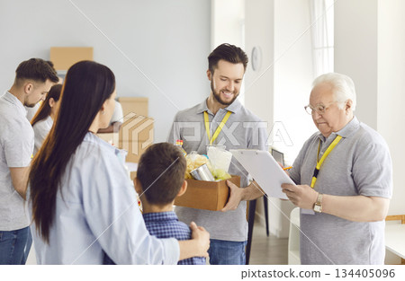 Volunteers giving free food donations for people in need in charitable foundation. Volunteers giving free food donations for people in need in charitable foundation. 134405096