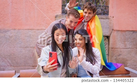 Diverse friends waving during video call with pride flag Diverse friends waving during video call with pride flag 134405322