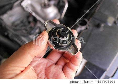 A hand holding a car radiator cap A hand holding a car radiator cap 134405394