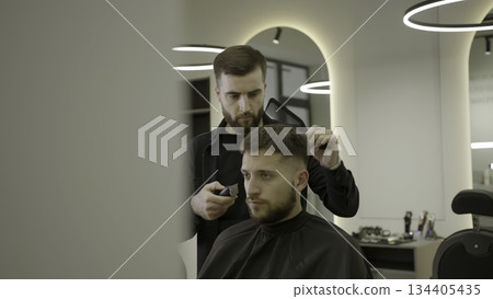 Professional barber giving haircut to client. Clip 134405435