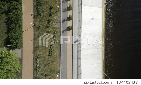 People walking along riverbank in urban park. Clip 134405438