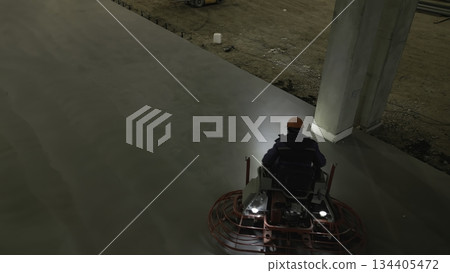 Construction worker using a ride on power trowel to finish concrete slab. Clip 134405472