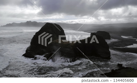 Powerful ocean waves crashing against a rocky island arch in iceland Powerful ocean waves crashing against a rocky island arch in iceland 134405600
