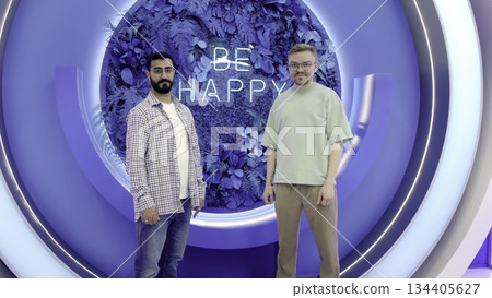 Two smiling men showing thumbs up in modern studio. Media 134405627