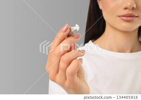 Woman shows a pin in her hand on a gray background 134405918