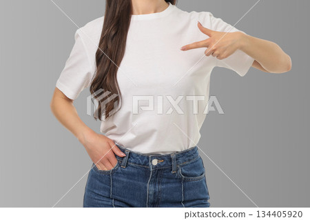 Woman points to empty space on t-shirt in studio backdrop 134405920