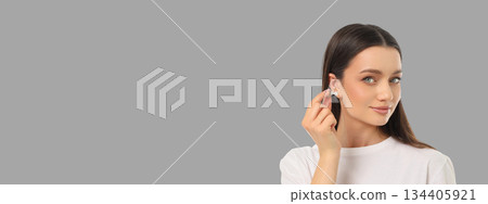 Woman applies earrings in a simple studio space 134405921