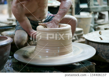 Selective focus on the clay work on the spinning tray with hands of worker Selective focus on the clay work on the spinning tray with hands of worker 134406137